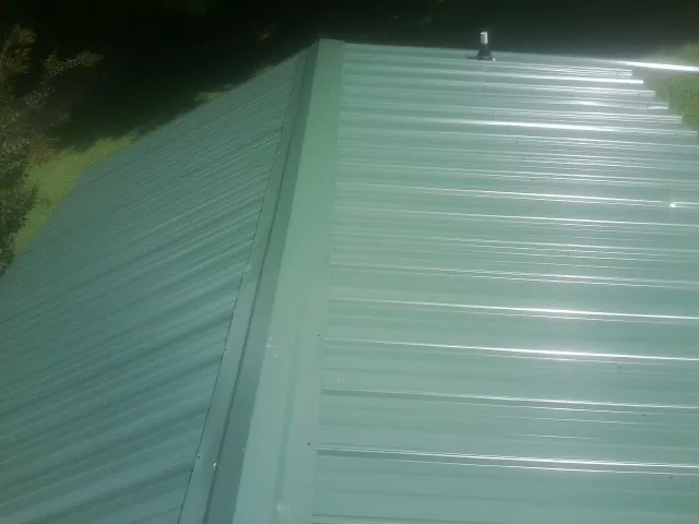 New green metal panels meeting at the ridge of a roof — Flat Roof Repair work by our crew in Lake Alfred