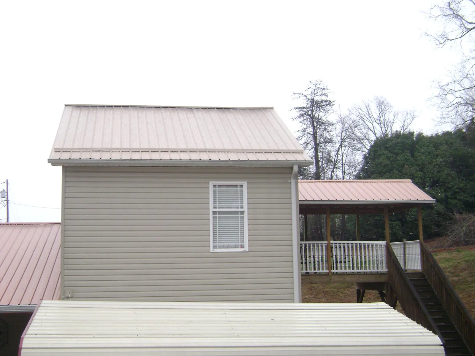 Tan metal roofs on a two story addition and attached porch, from a Roof Replacement job in Lake Alfred