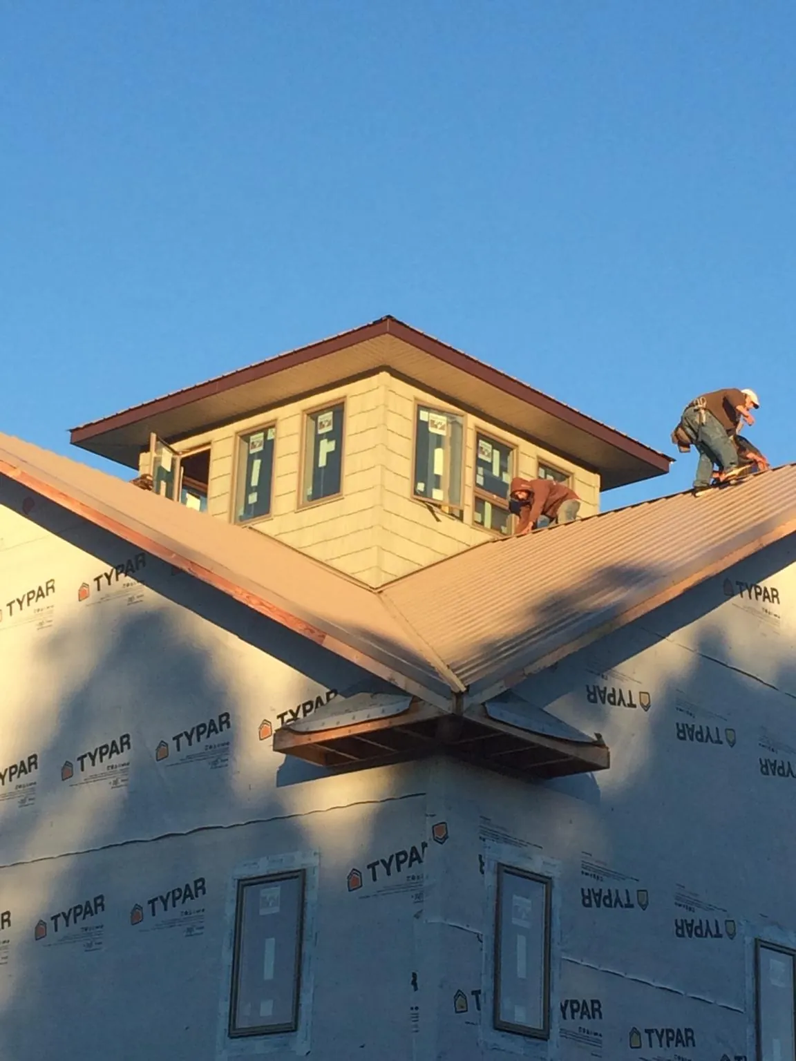 Roofers working around a rooftop cupola on a new metal roof at sunset — Roof Waterproofing in Lake Alfred by Roofing Brothers